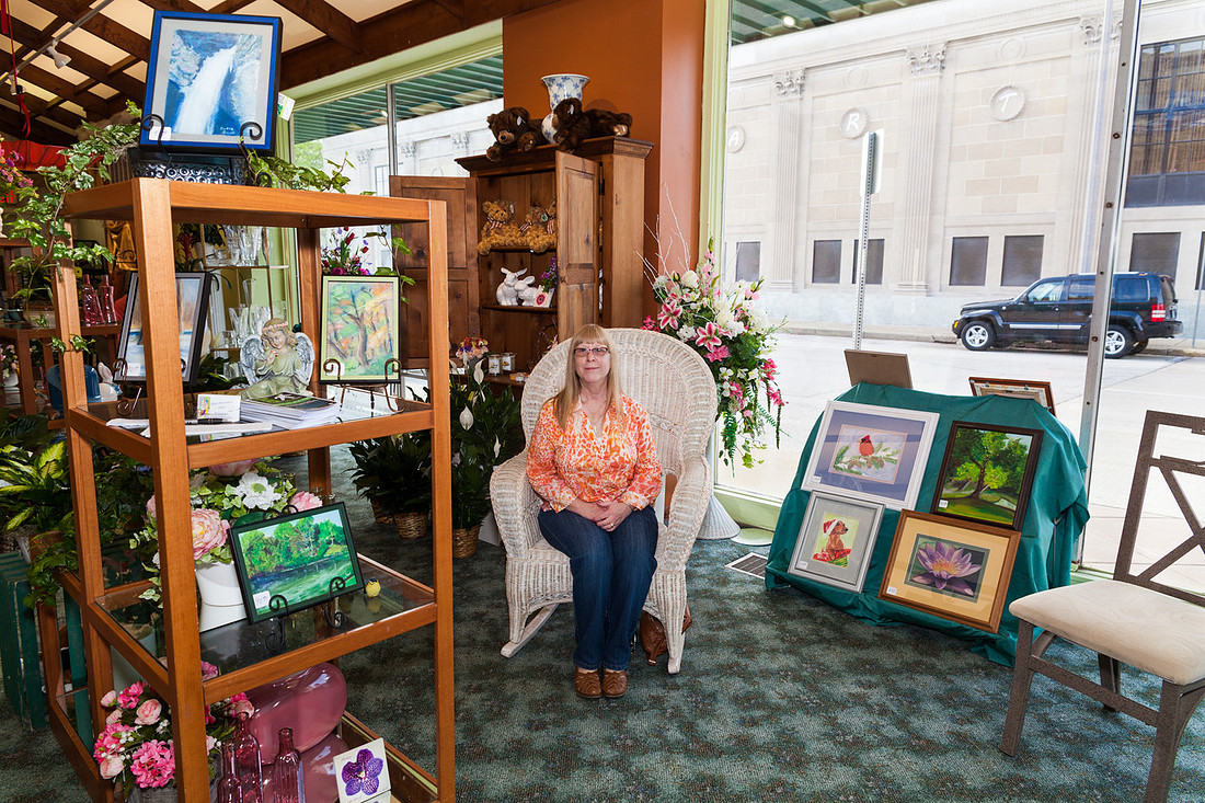 picture of artist sitting with her paintings