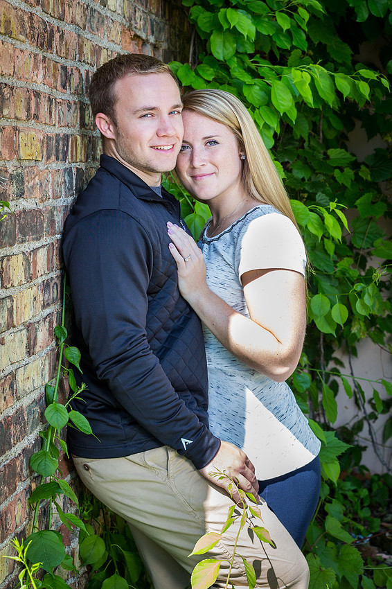 engaged couple leaning against the wall