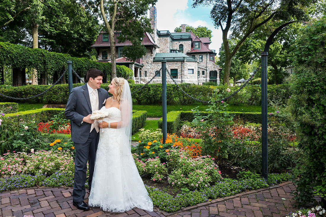photograph of bride looking at groom by a garden 