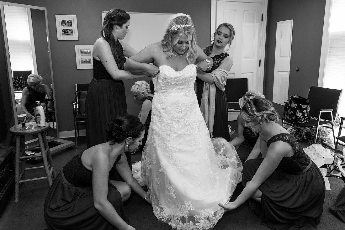 photo of bridesmaids helping the bride into her dress
