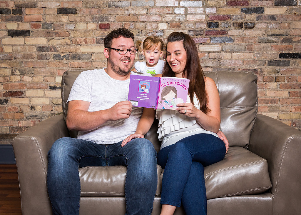 picture of mom and dad reading book to little girl