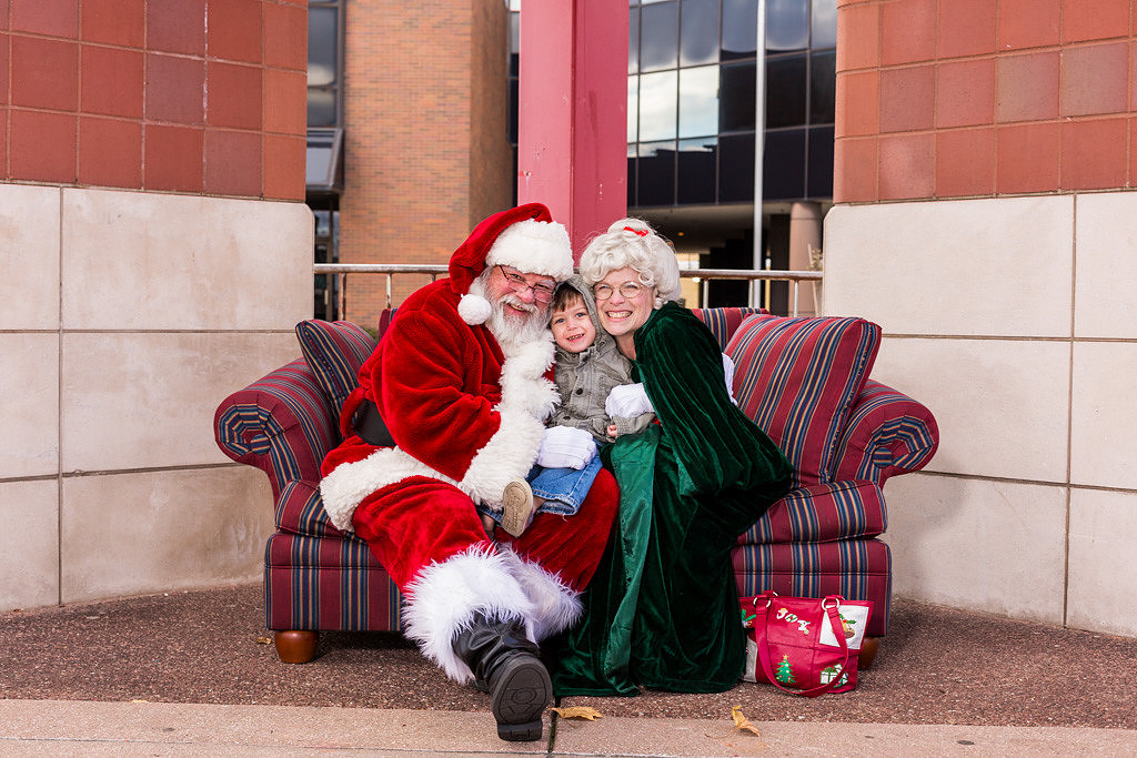 picture of a small child between Santa and Mrs. Claus