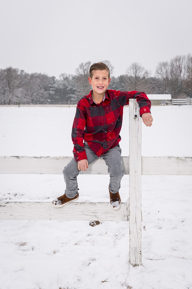 picture of boy sitting on fens in the snow.
