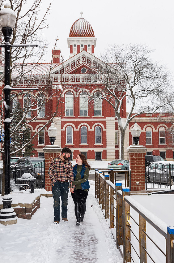 engagement picture of couple walking in front of city hall