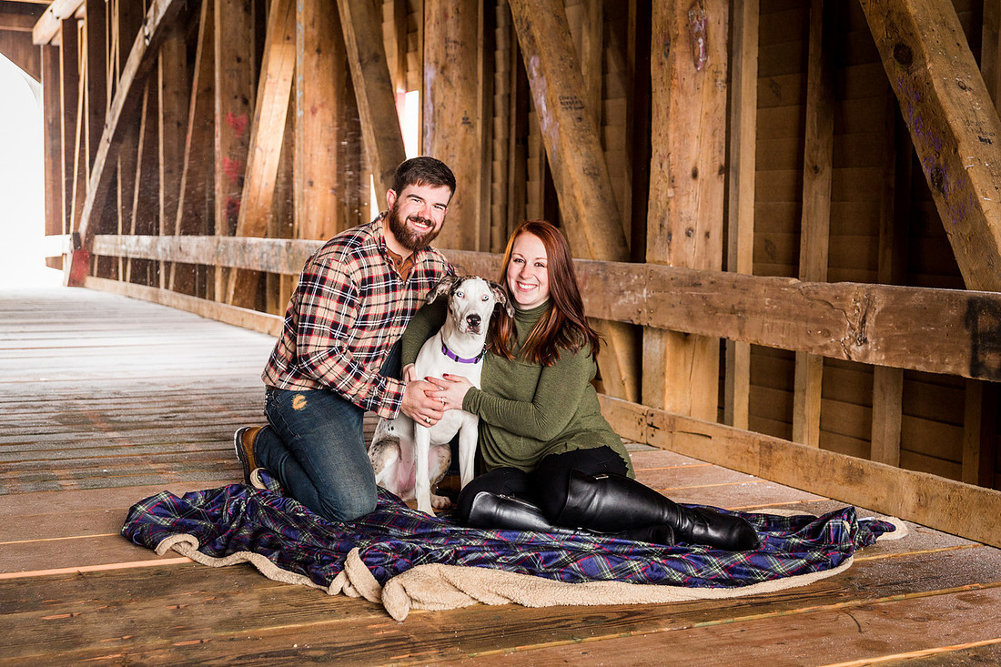 picture of couple with their dog in a covered bridge during engagement photo session
