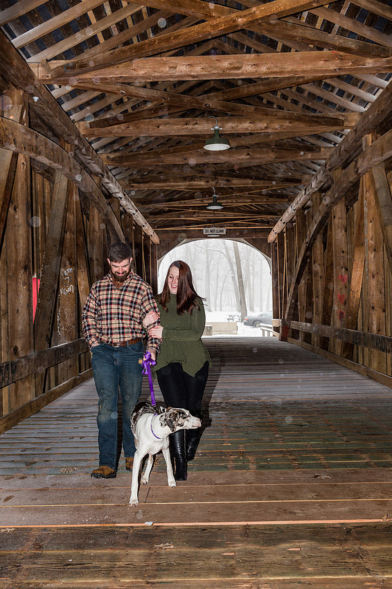 Picture of a couple walking a dog in a covered bridge