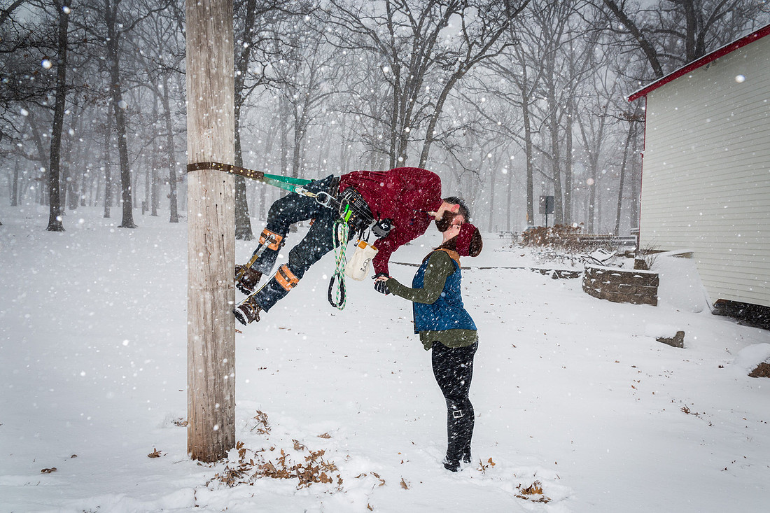 image of girl kissing telephone poll climber in the snow
