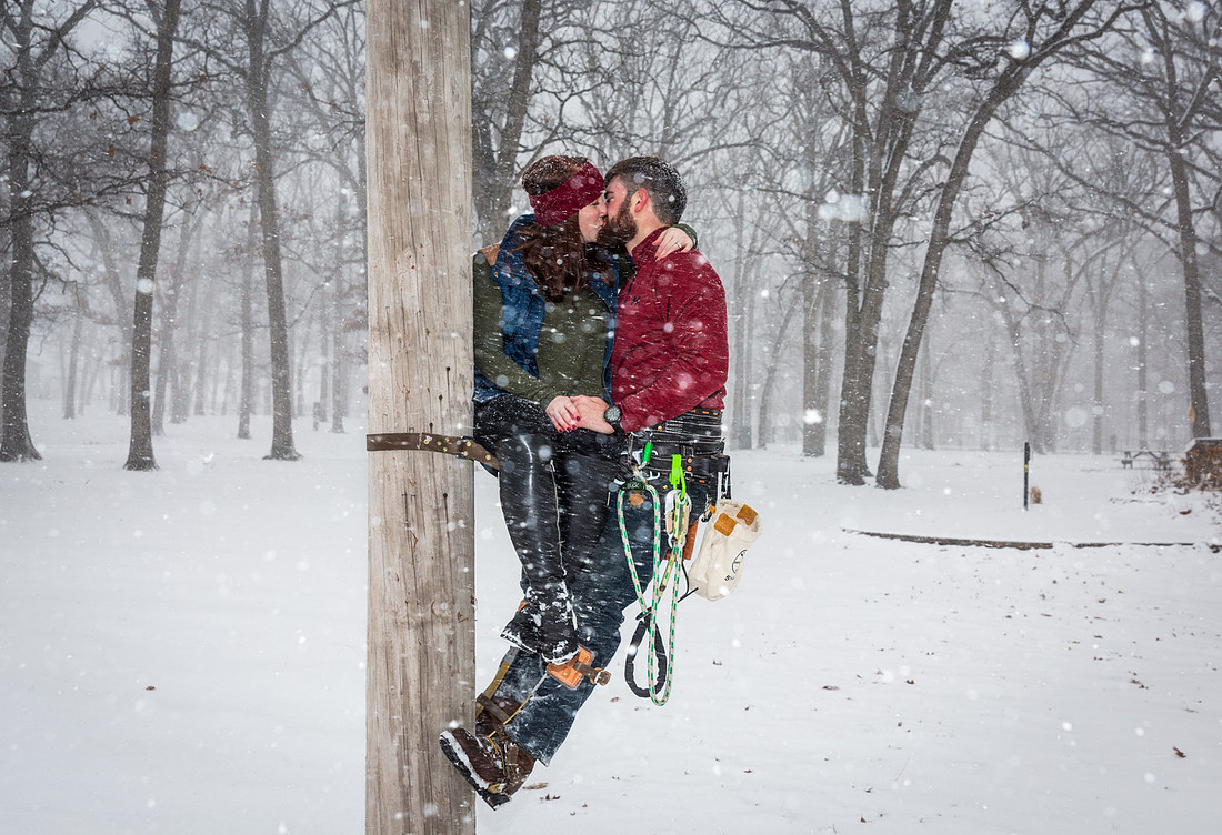 image of engagement photo session of a couple kissing while on a telephone poll