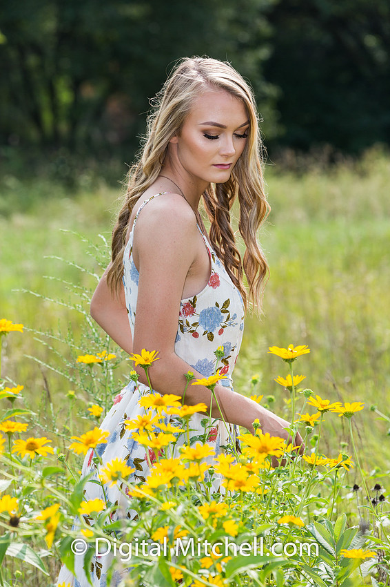 photograph of a high school senior posing in a field of tall, yellow flowers