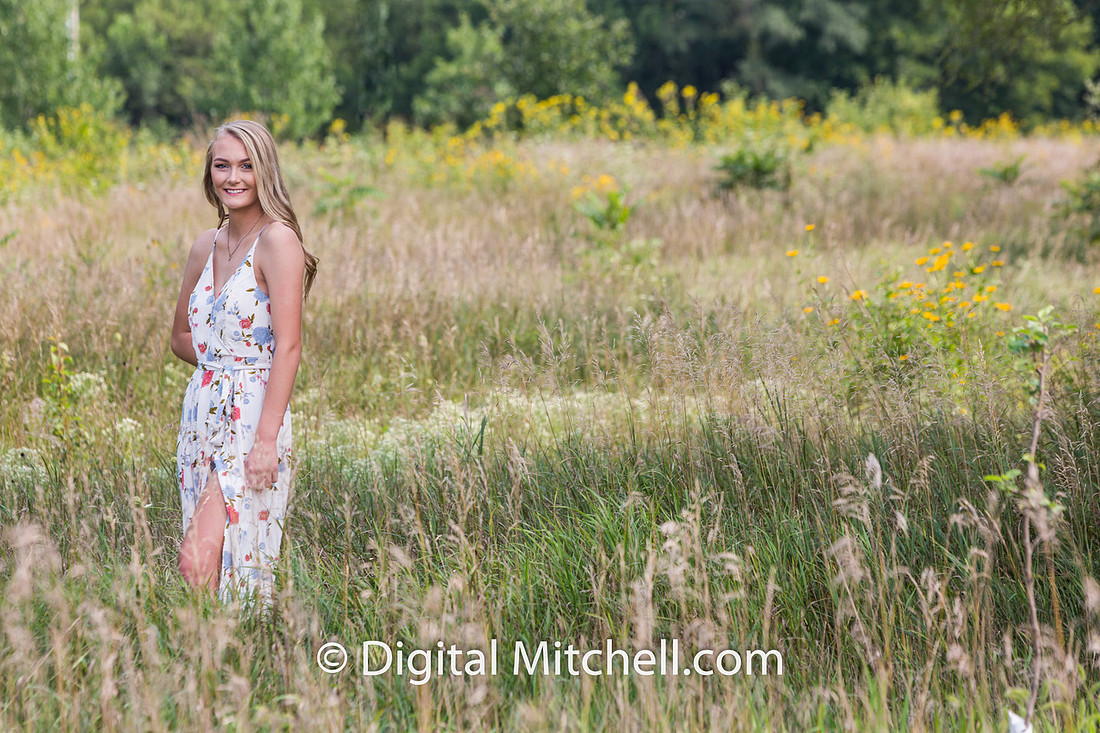 photograph of a high school senior posing in a field of tall, yellow flowers