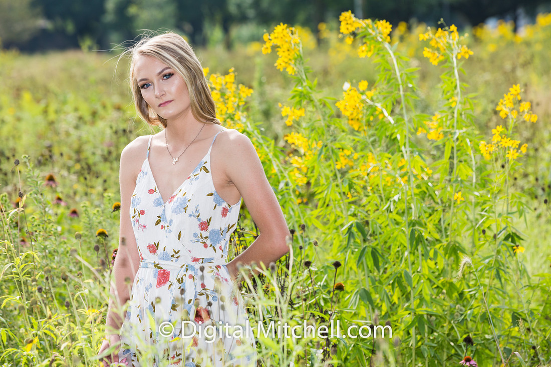photograph of a high school senior posing in a field of tall, yellow flowers