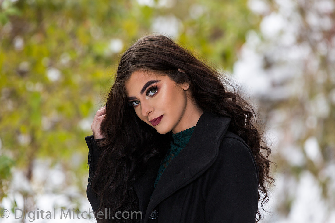 Photograph Lovely young lady in a dark coat in the snow