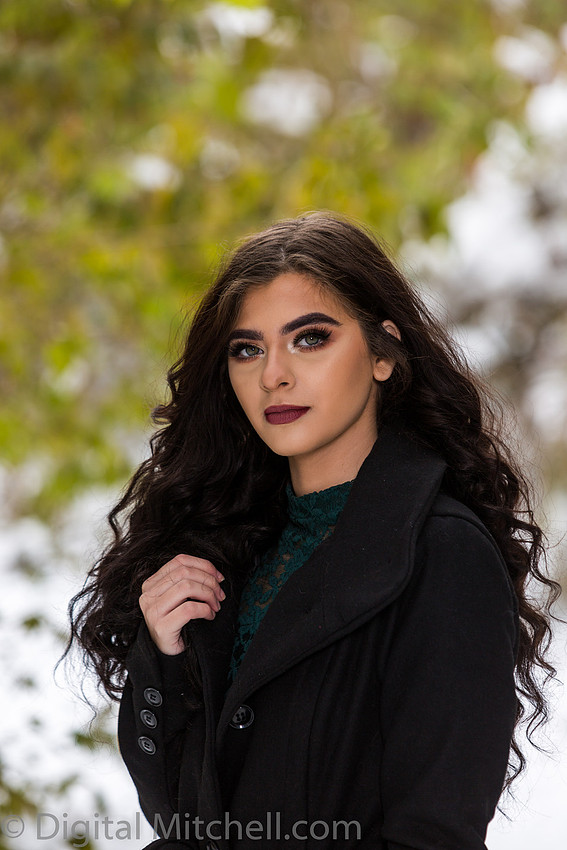 Photograph Lovely young lady in a dark coat in the snow