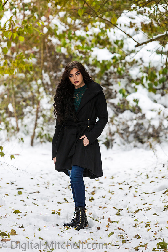 Photograph Lovely young lady in a dark coat in the snow