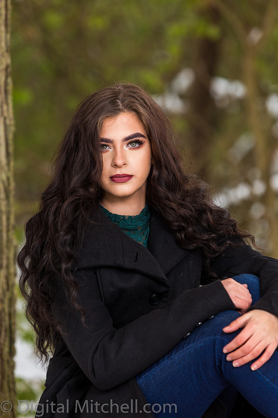 Photograph Lovely young lady in a dark coat in the snow