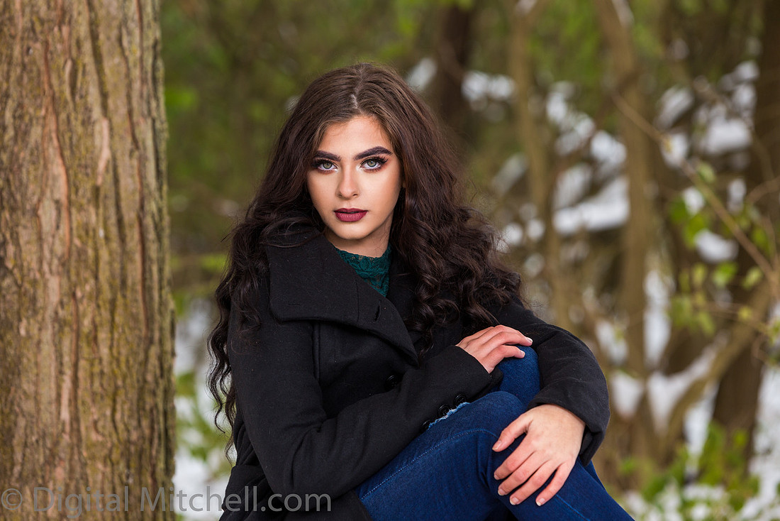 Photograph Lovely young lady in a dark coat in the snow