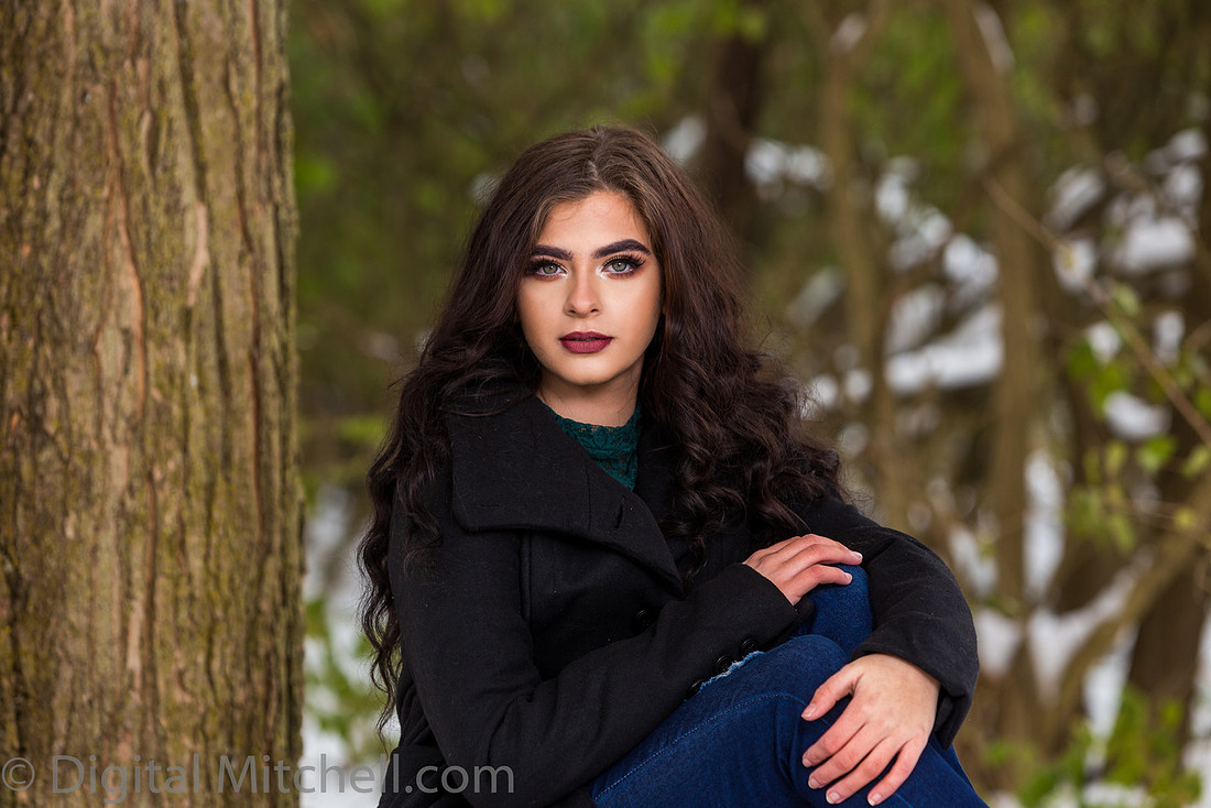 Photograph Lovely young lady in a dark coat in the snow